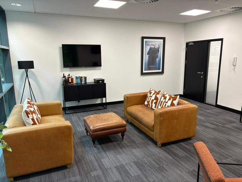 Lounge area with tan leather sofas and a flat-screen TV.