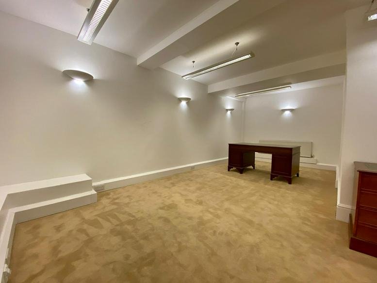 Spacious private office at Grosvenor Gardens with white walls and a dark wood executive desk.