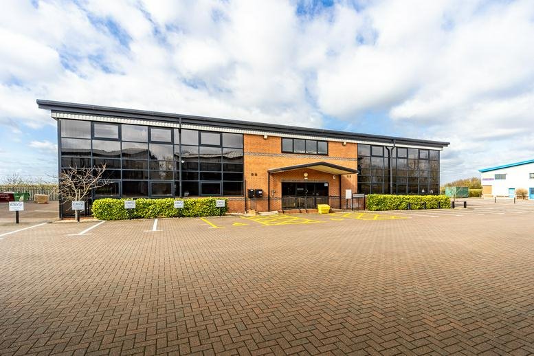 Exterior view of a modern brick office building with reflective glass windows.