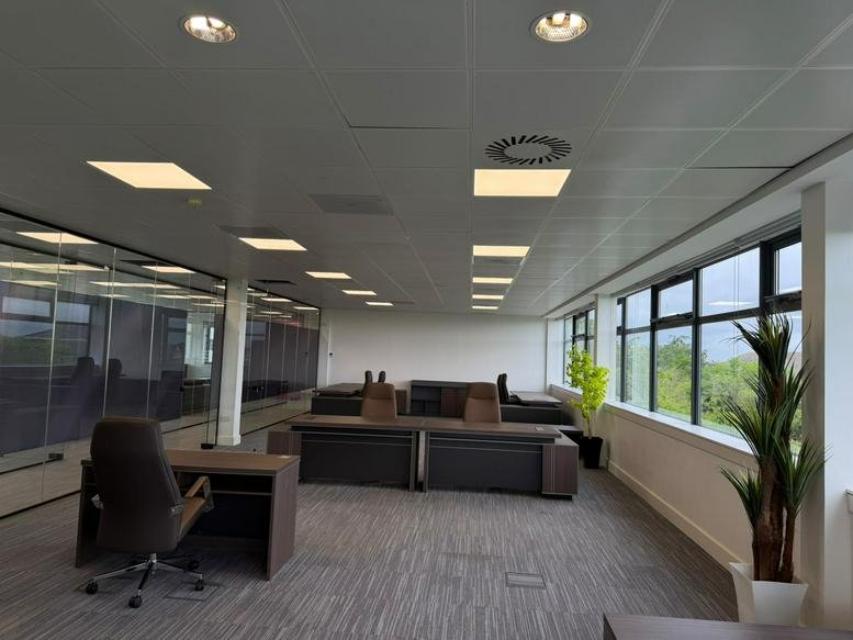 Spacious office workspace with dark wood desks and natural light from large windows at Hermiston Quay, 5, Cultins Road.