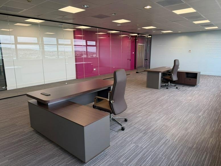 Spacious private office at Hermiston Quay, 5, Cultins Road with modern desks and a vibrant pink feature wall.