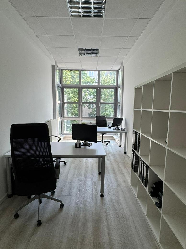 Private office at Huttenstraße with two desks, ergonomic chairs, and large windows.