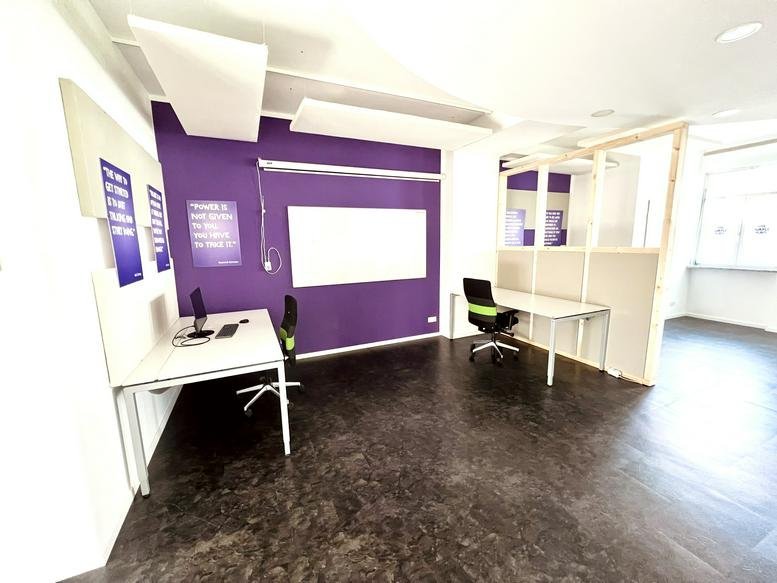 Spacious office workspace at Jugendheimweg 3b featuring a purple feature wall and modern white desks.