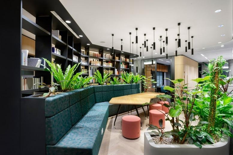 Spacious communal lounge at Junghofstraße 9 featuring green banquette seating and lush indoor plants.
