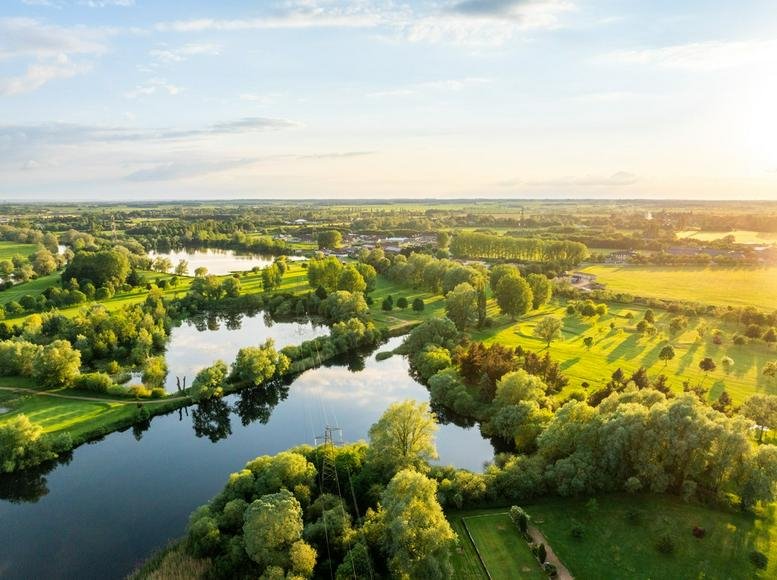 Wide aerial view of the Knowledge Centre, Wyboston Lakes, surrounded by lush greenery and lakes.