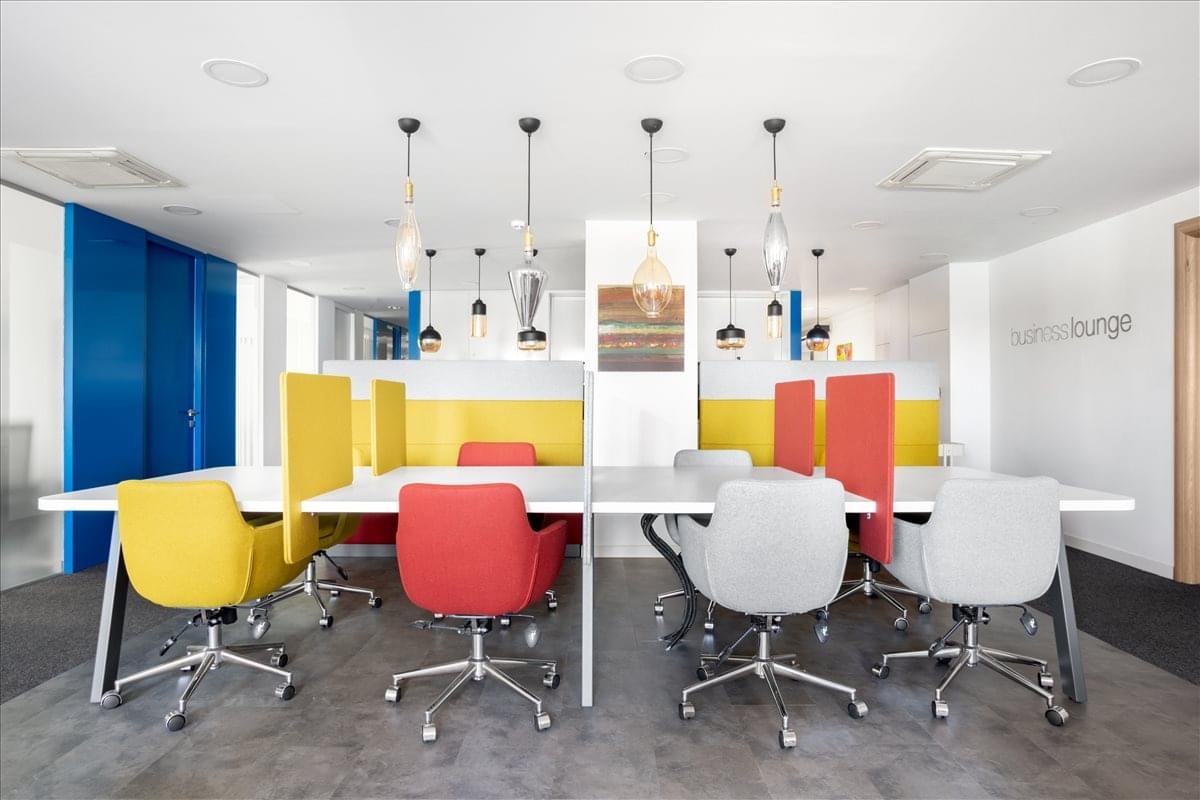 Vibrant communal breakout area with colorful yellow and red seating and hanging pendant lights.