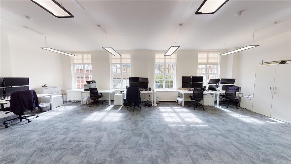 Spacious open-plan workspace at 1-2 Castle Lane with large windows and multiple computer workstations.