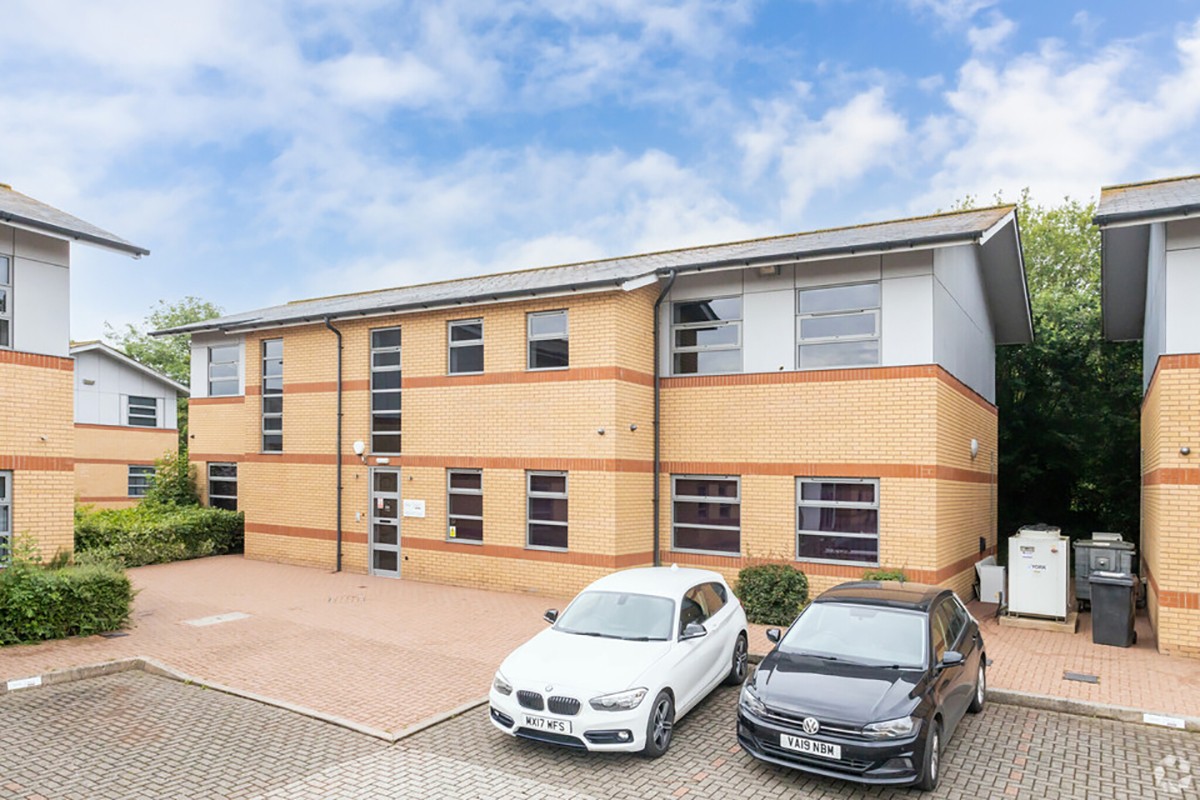 Front view of the office building entrance with cars parked in front.