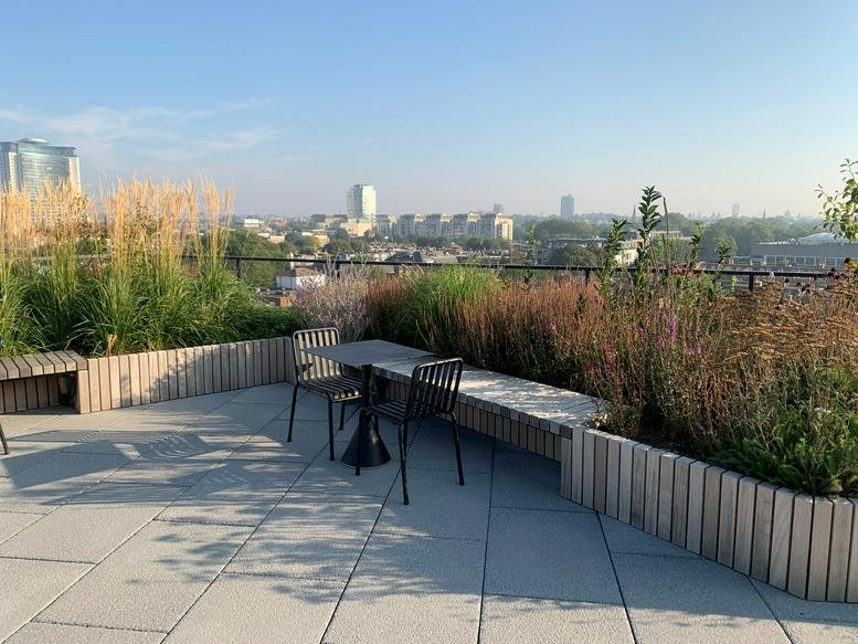 Rooftop garden area with grey tiles and lush perimeter planting.