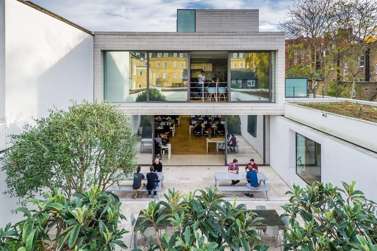 Modern exterior of 31 Vernon Street, Hammersmith and Fulham featuring a glass facade and lush courtyard greenery.