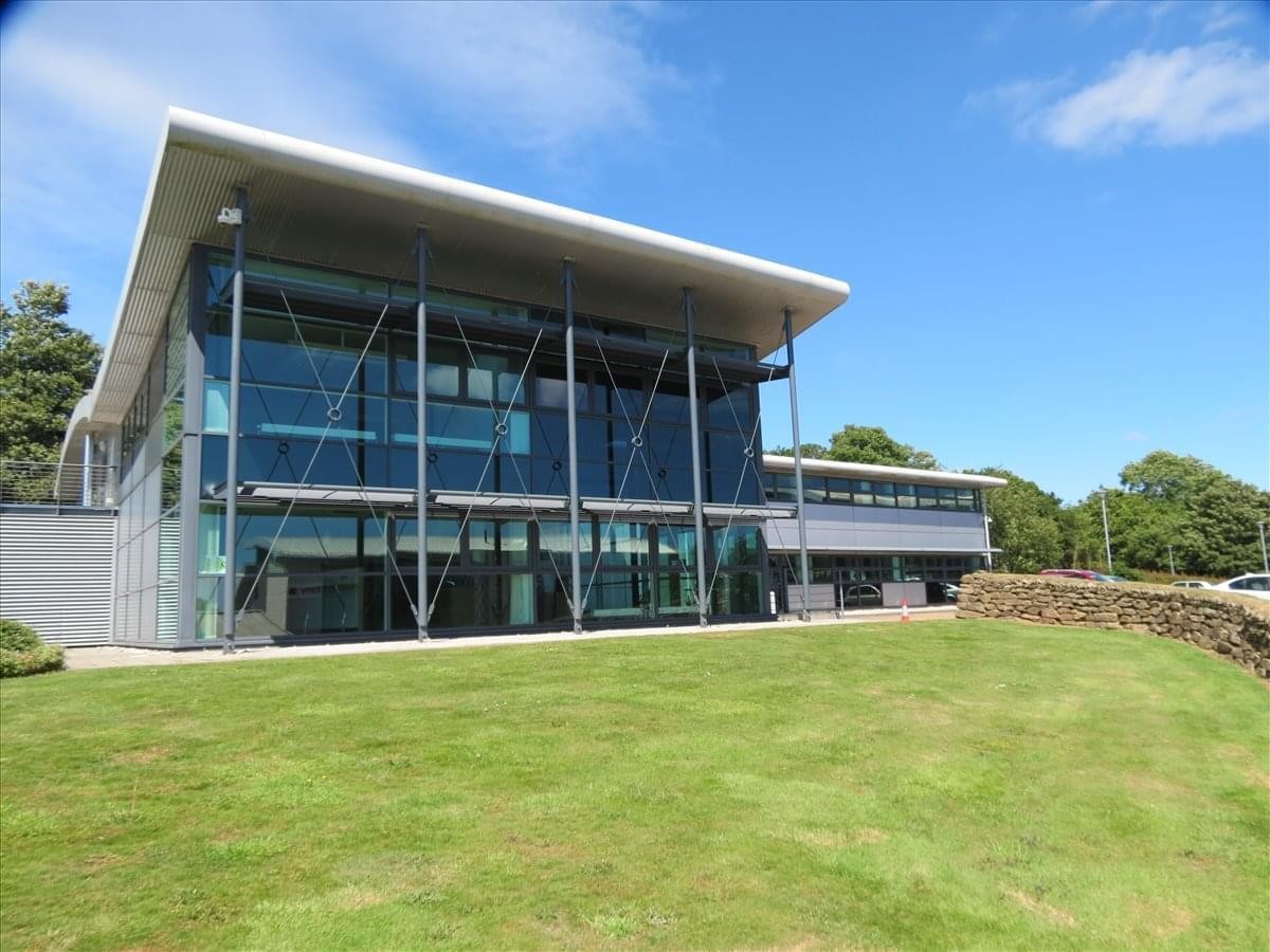 Modern glass exterior of 5 Research Way, Plymouth Science Park, Derriford with a slanted roof and green lawn.