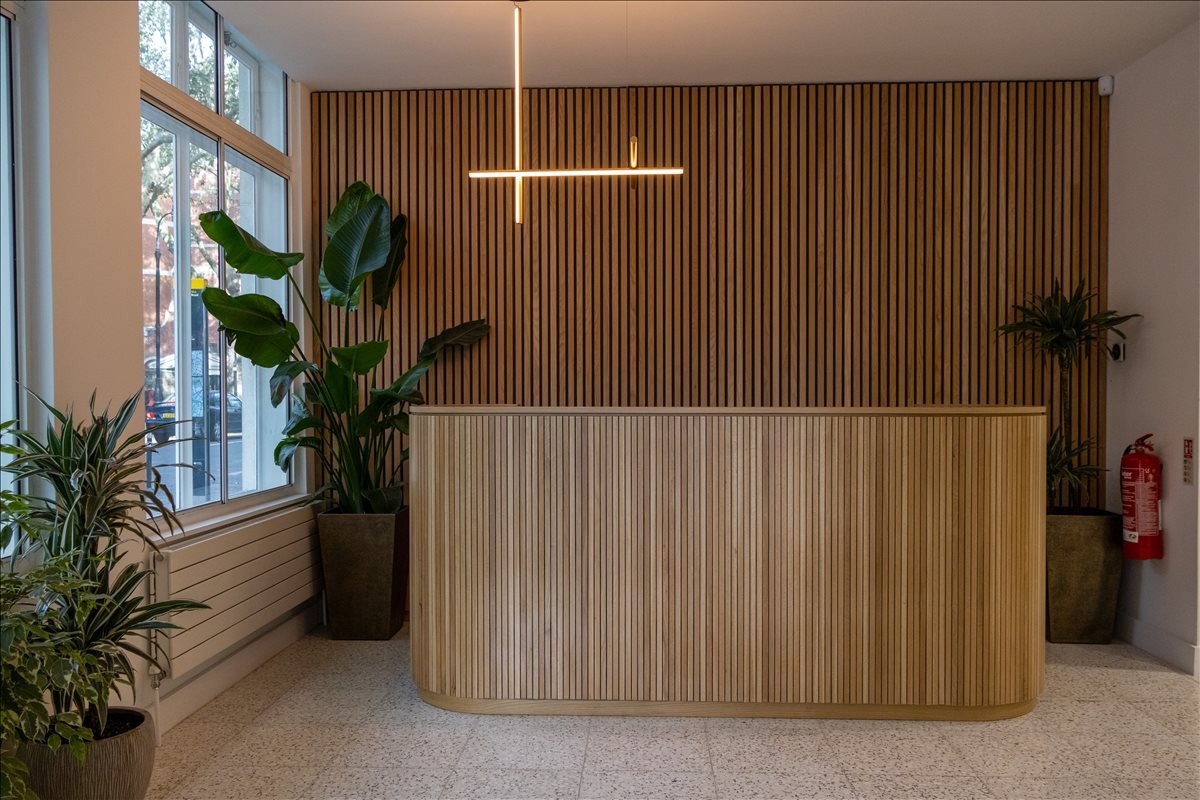 Wood-slatted reception area at 80-86 Gray’s Inn Road with modern lighting and leafy plants.
