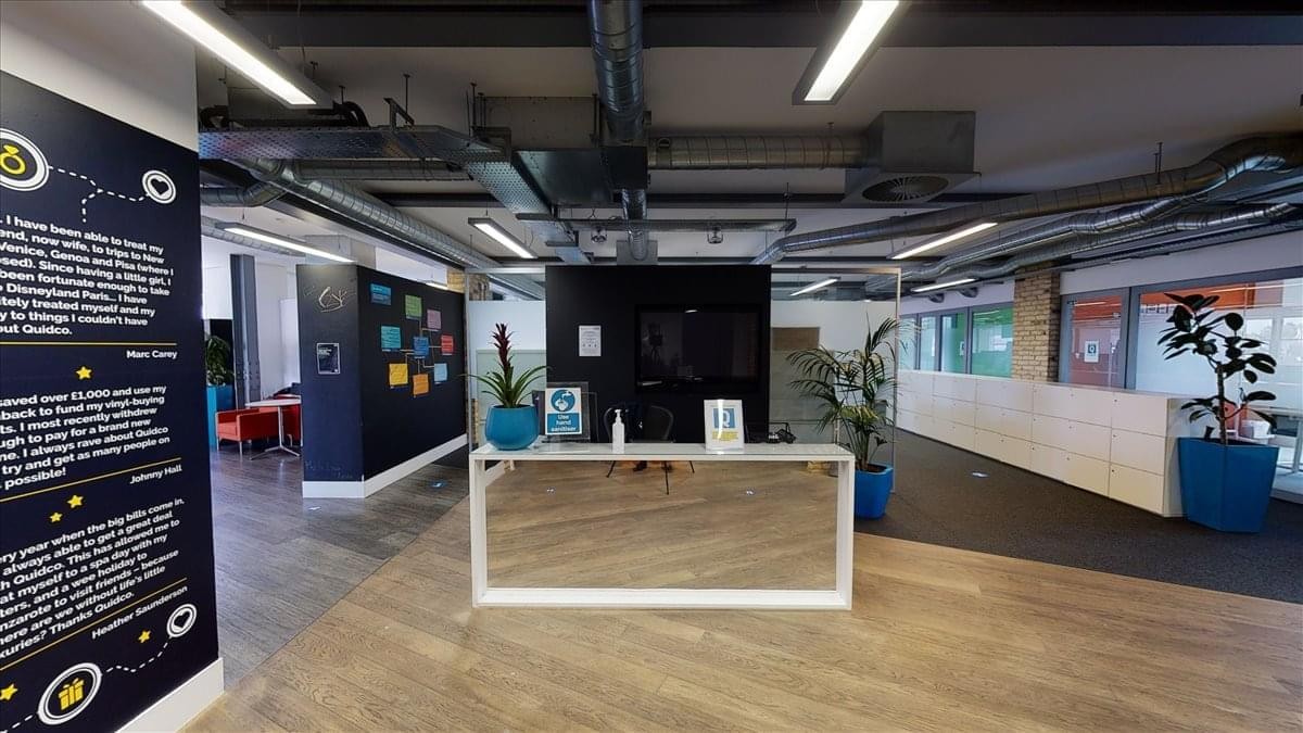 Reception area at 80 Great Eastern Street with a wood-panelled desk and modern industrial ceiling.