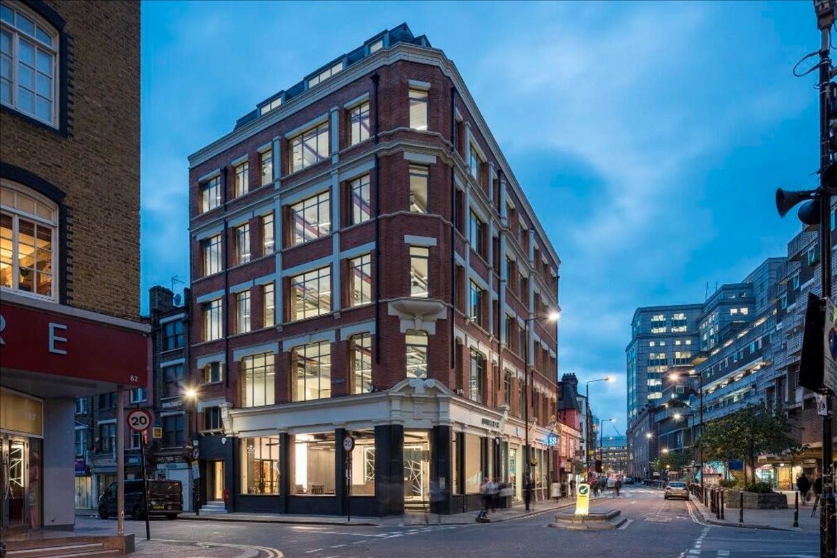 Exterior view of the historic red brick building at 80 Middlesex Street with lit windows at dusk.