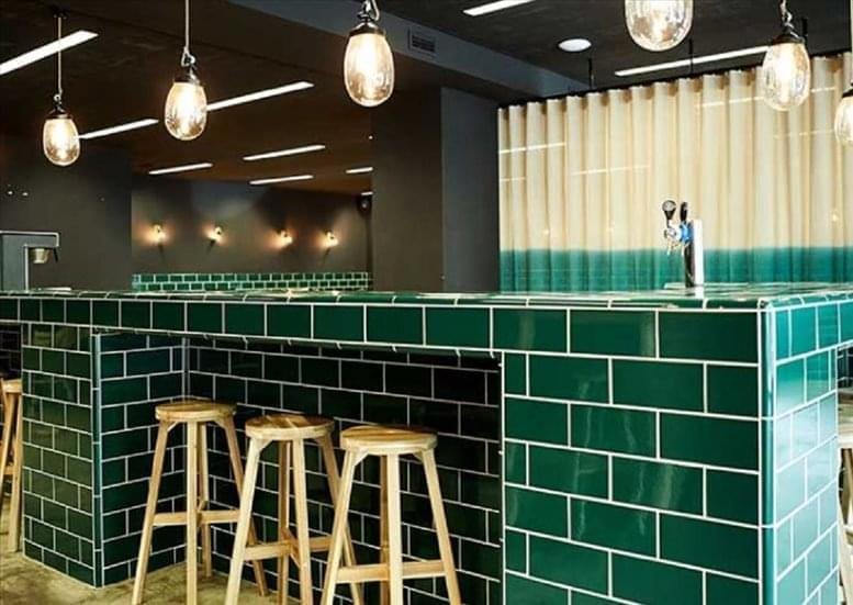 A stylish breakout area at 80 Old Street, London featuring a green tiled bar and wooden bar stools.