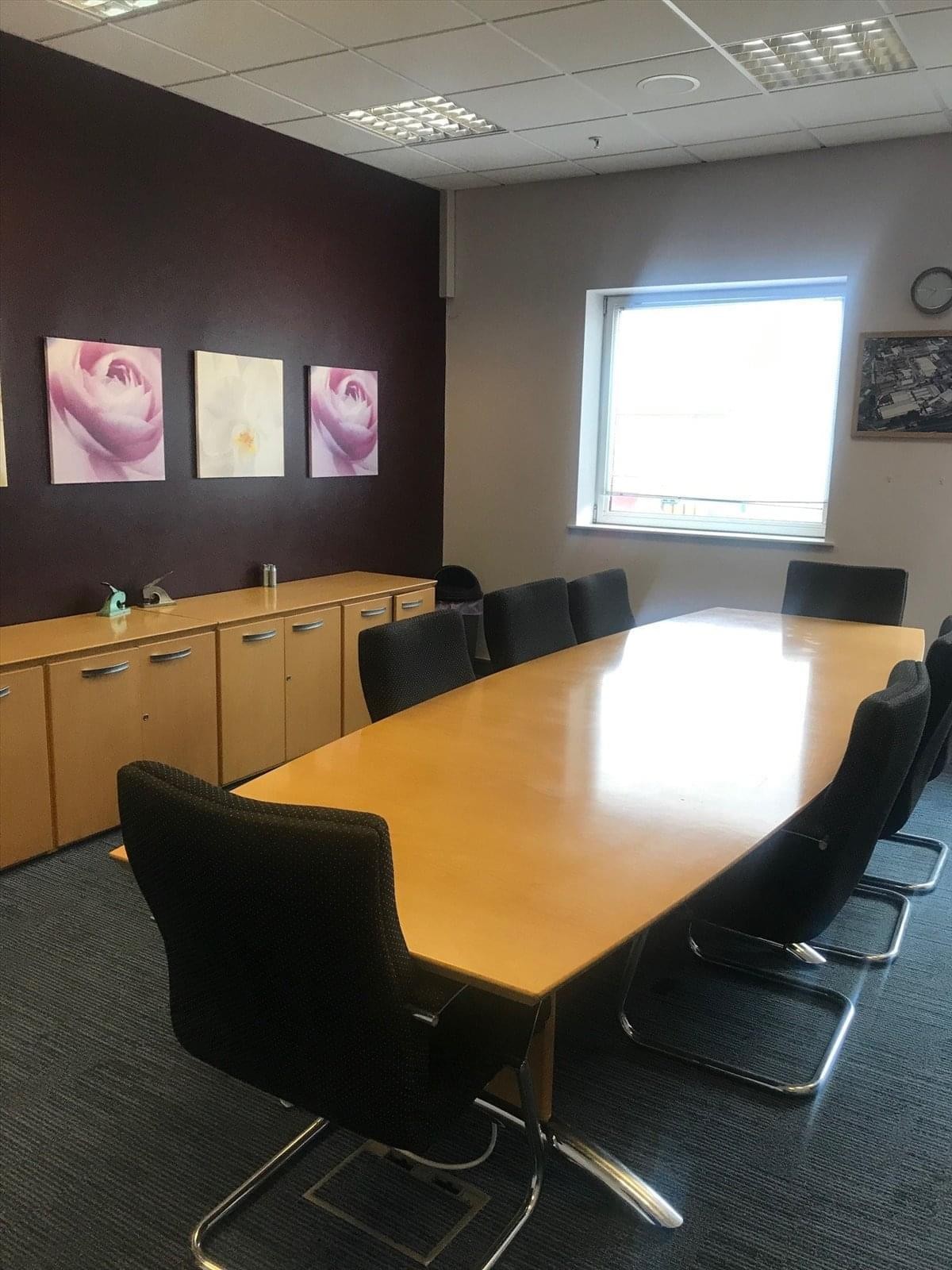 Spacious boardroom at Avana Business Centre, Rogerstone, Newport with a purple feature wall and floral artwork.