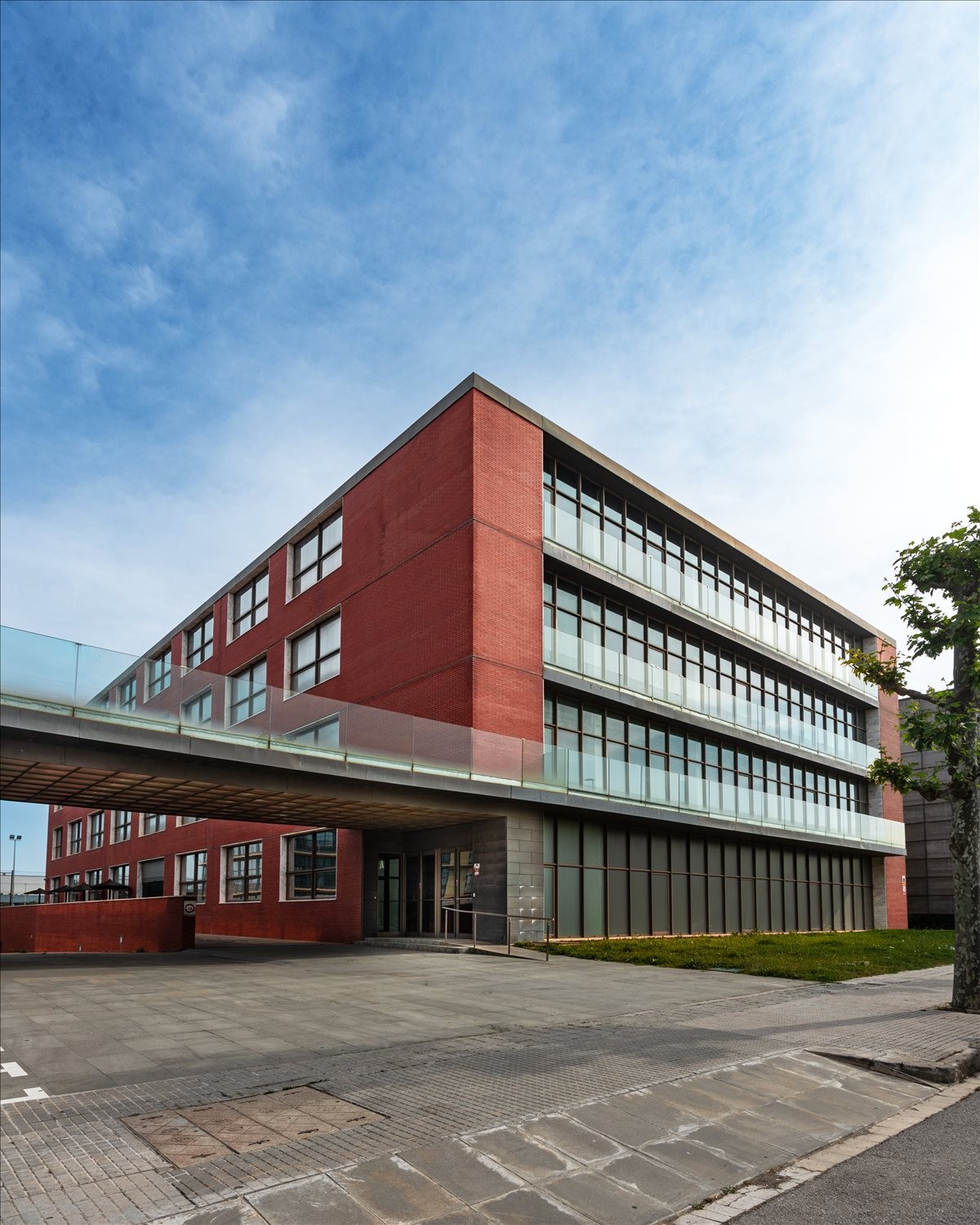 Angular view of the building exterior showing a glass-walled skybridge and a brick facade under a blue sky.