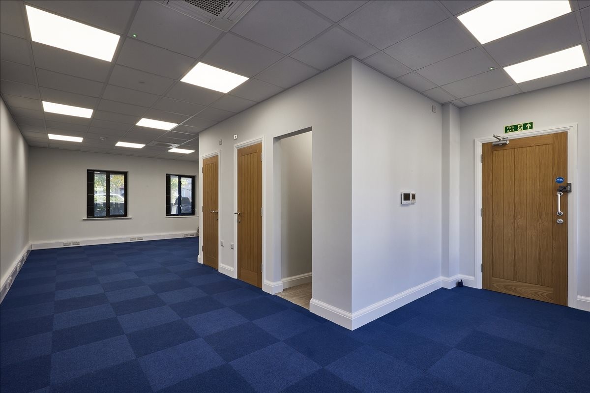 Spacious interior at Bessborough Road, Harrovian Business Village with blue carpet tiles and recessed lighting.