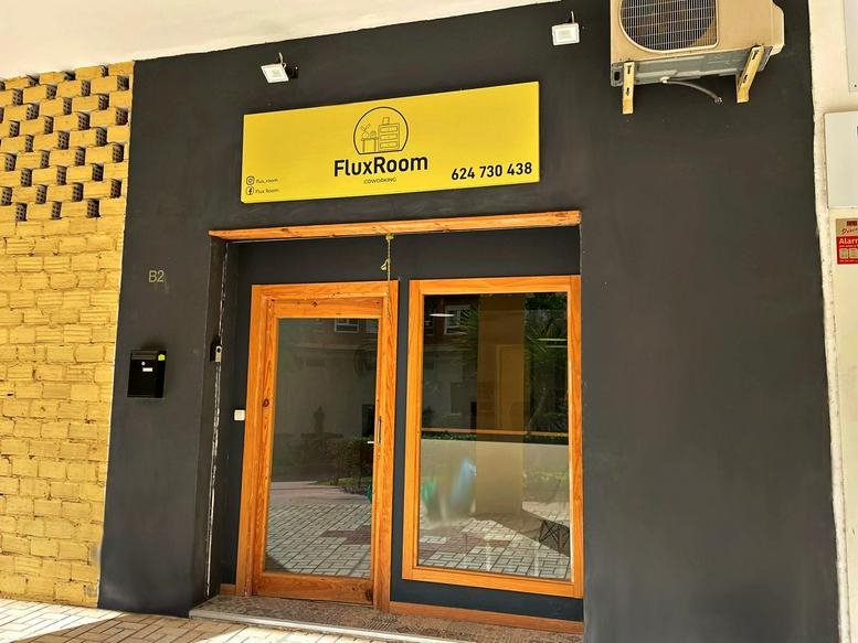 Exterior entrance of the FluxRoom office with dark gray walls and yellow signage.