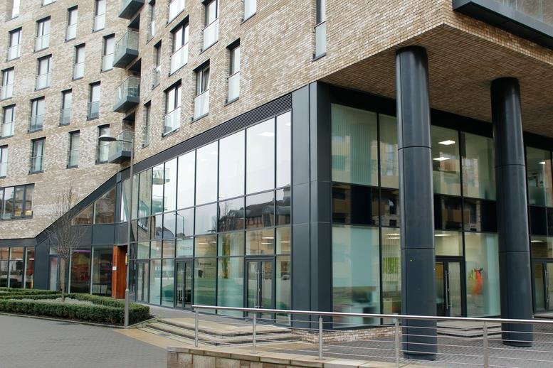 Ground floor exterior showing the glass-fronted office entrance with tall black support columns.