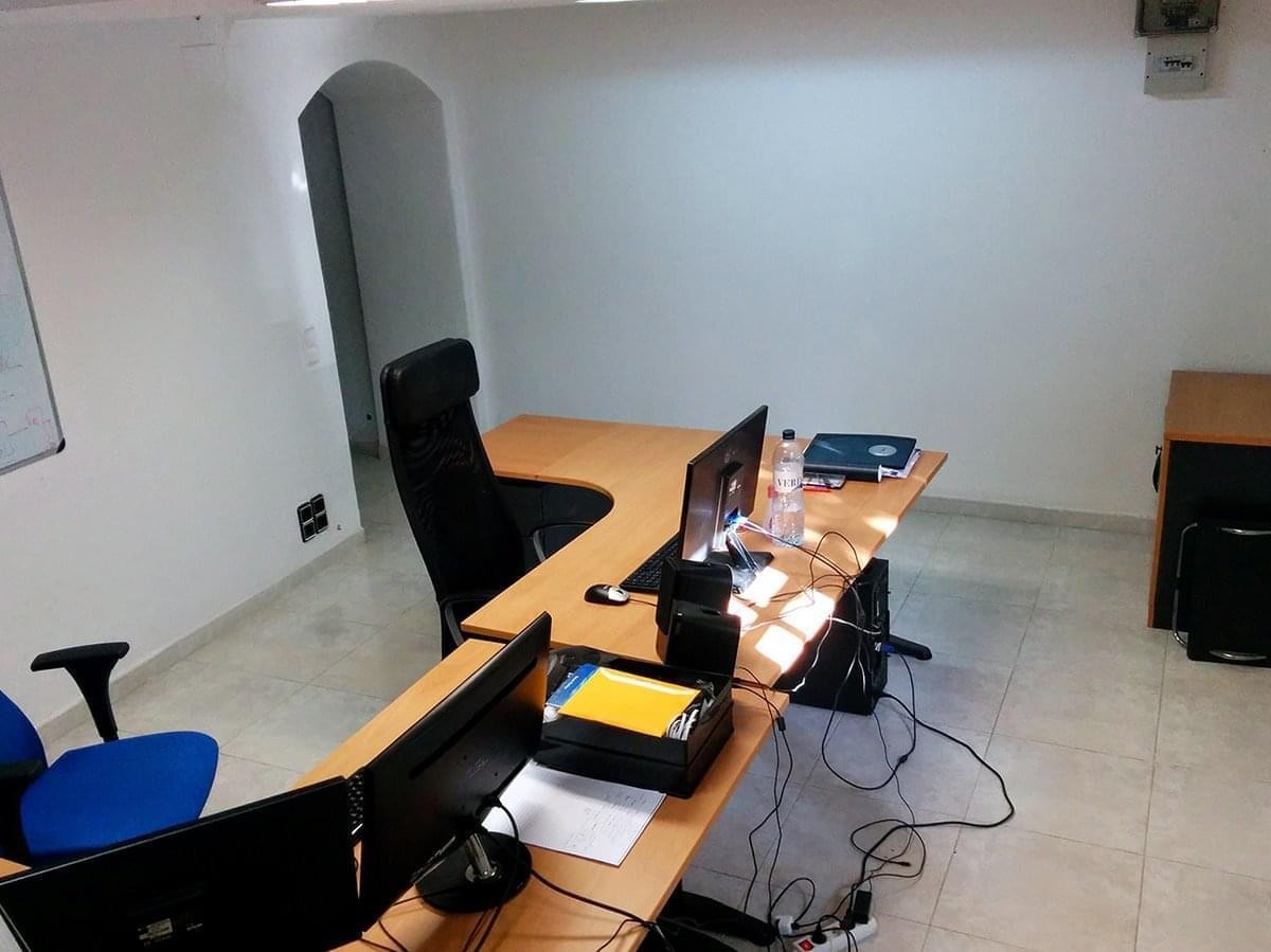 Bright workspace at Carrer Bilbao 7 with an L-shaped wooden desk and professional seating.