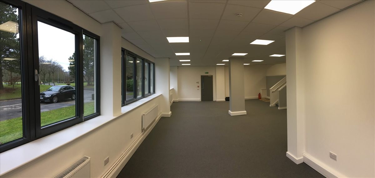 Spacious interior office at Elliott House, Kilwinning Road, Irvine, with multiple windows and grey carpeting.