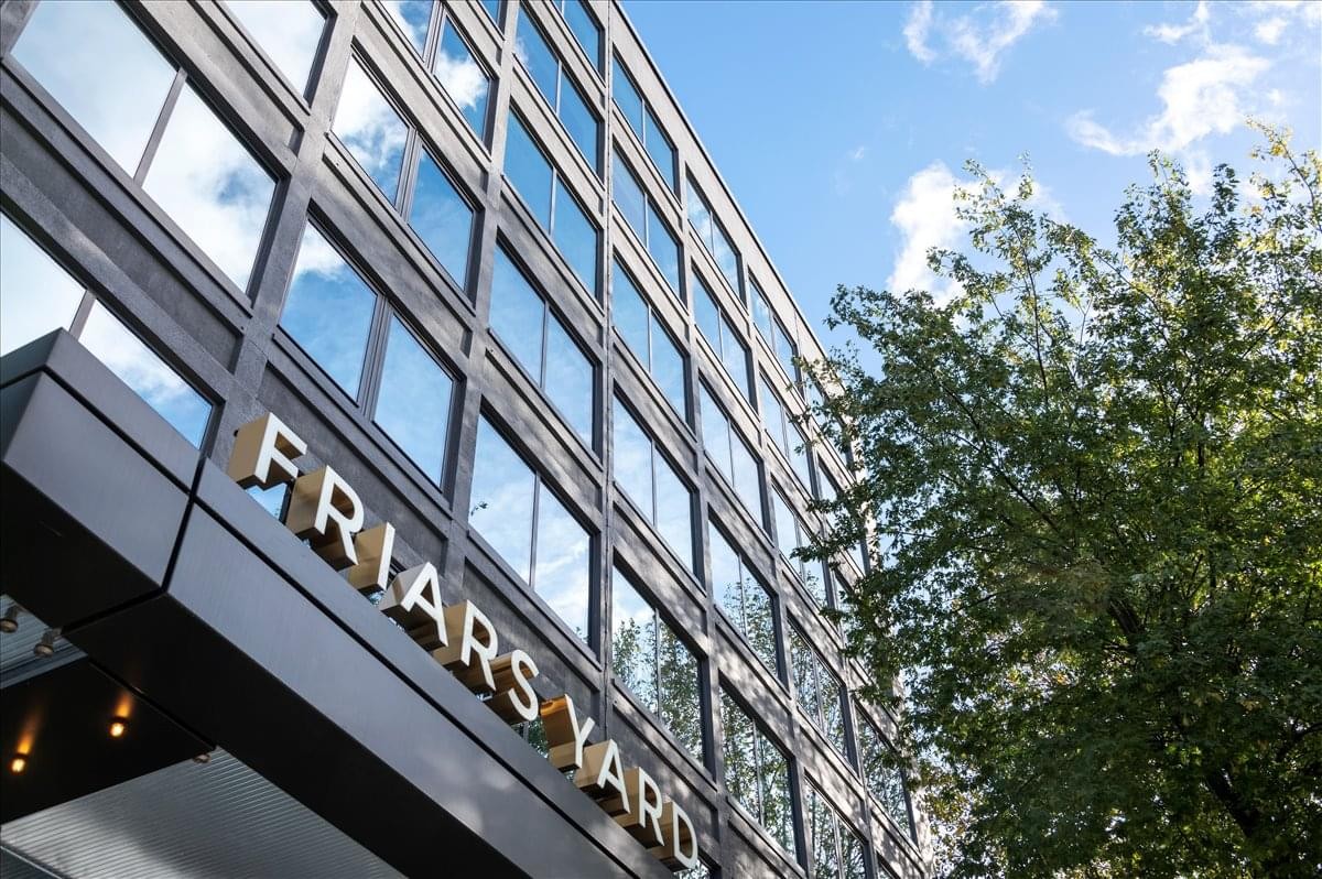 Exterior view of the glass-fronted Friars Yard building with mature trees.