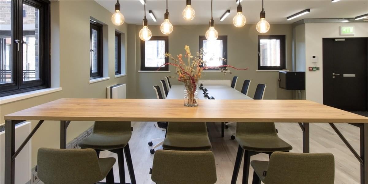 Spacious boardroom at Hatchers Yard, Unit B5, featuring a long wood table and industrial pendant lighting.