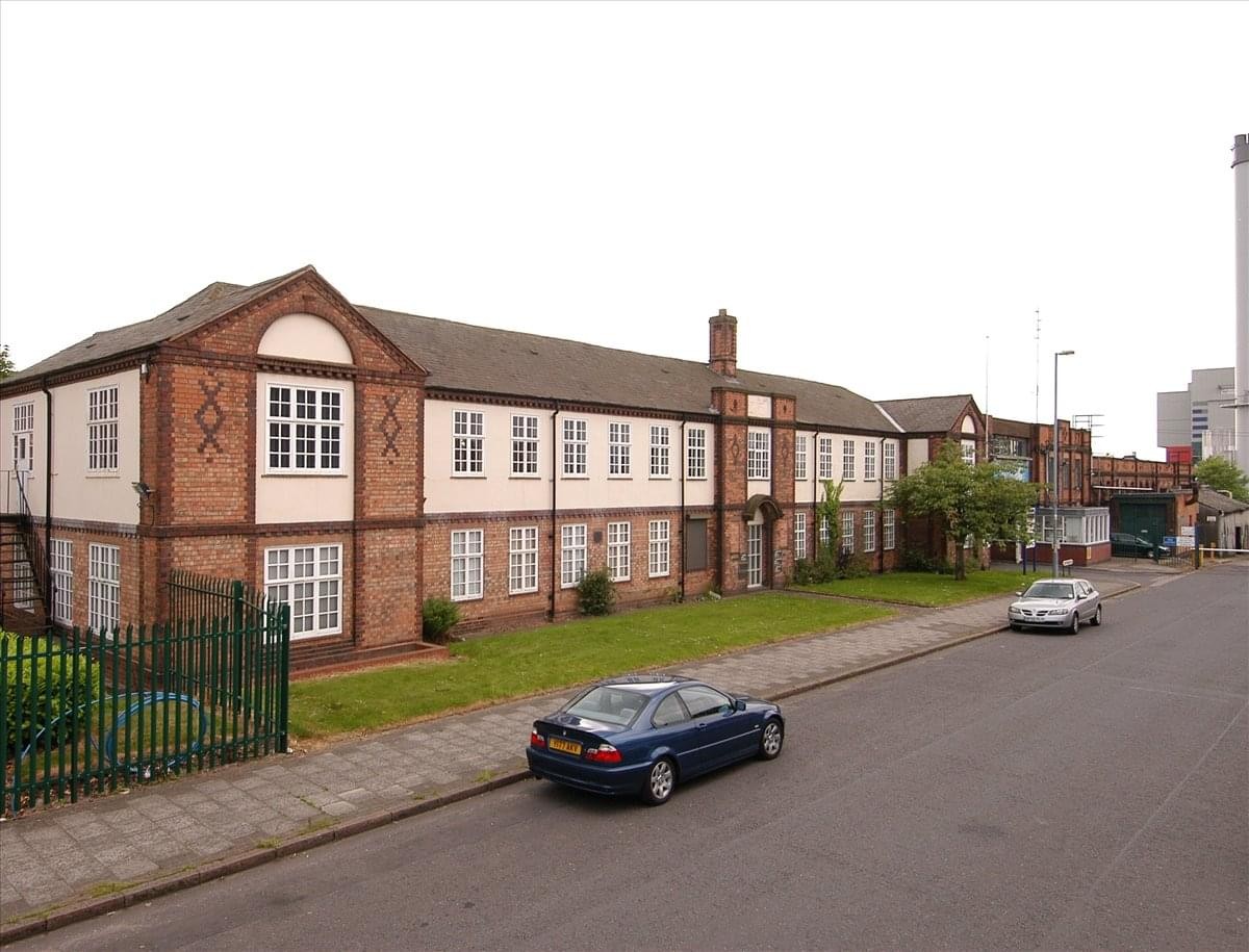 Wide exterior shot of the two-story brick office building and parking area.