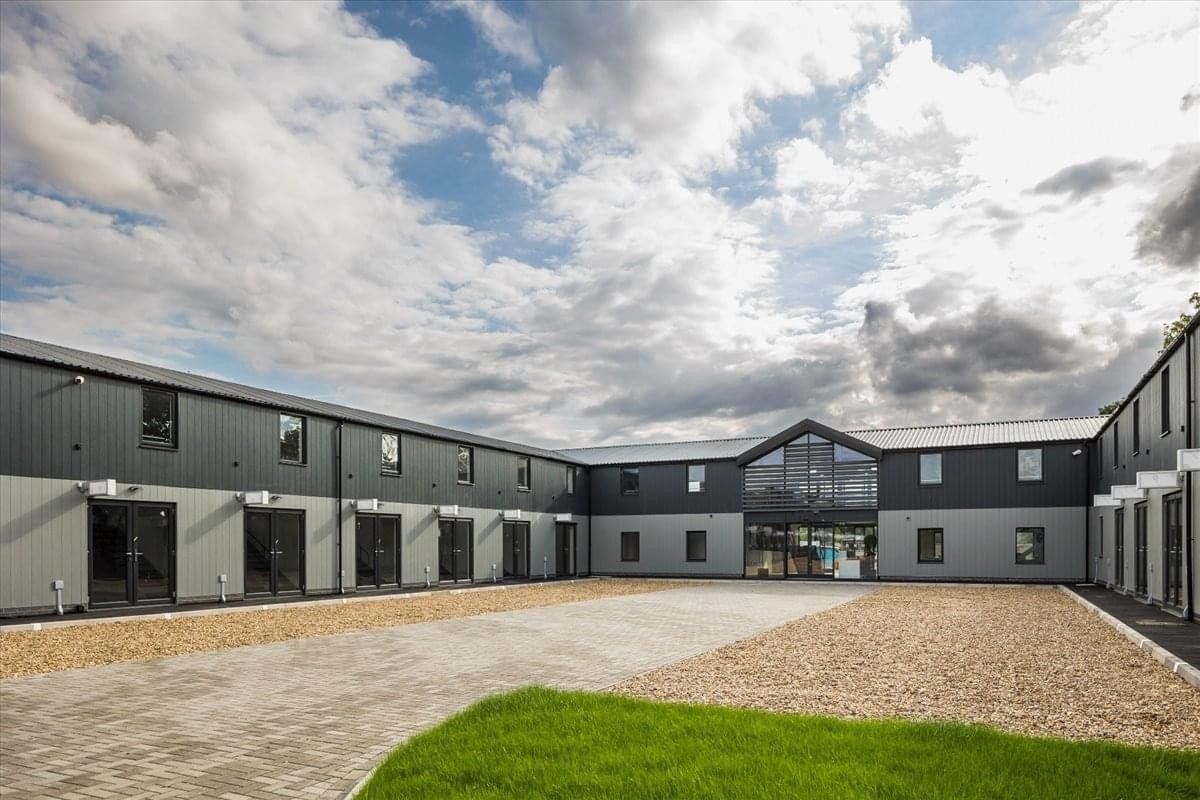 Exterior view of the contemporary Mayfly Way, Old Ipswich Road building featuring a gray facade and gravel courtyard.