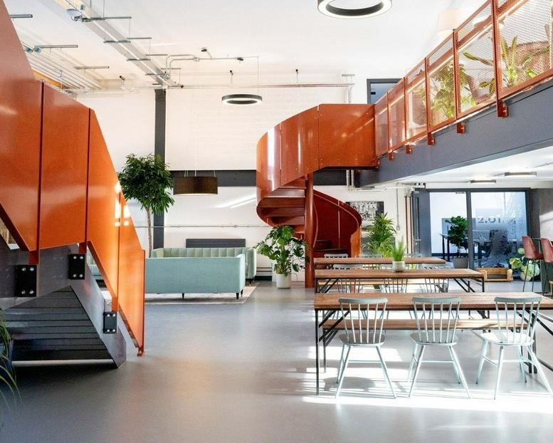 Spacious communal area at Newark Works featuring a striking orange spiral staircase and lounge seating.