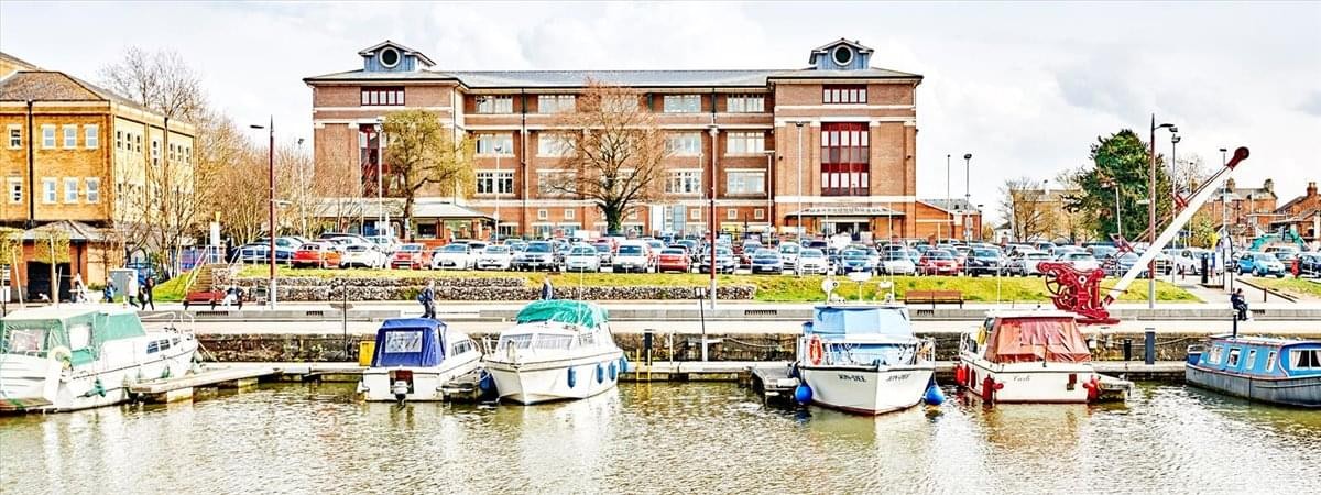 Exterior view of the brick facade of Southgate House, Southgate Street, Gloucester across a marina with boats.