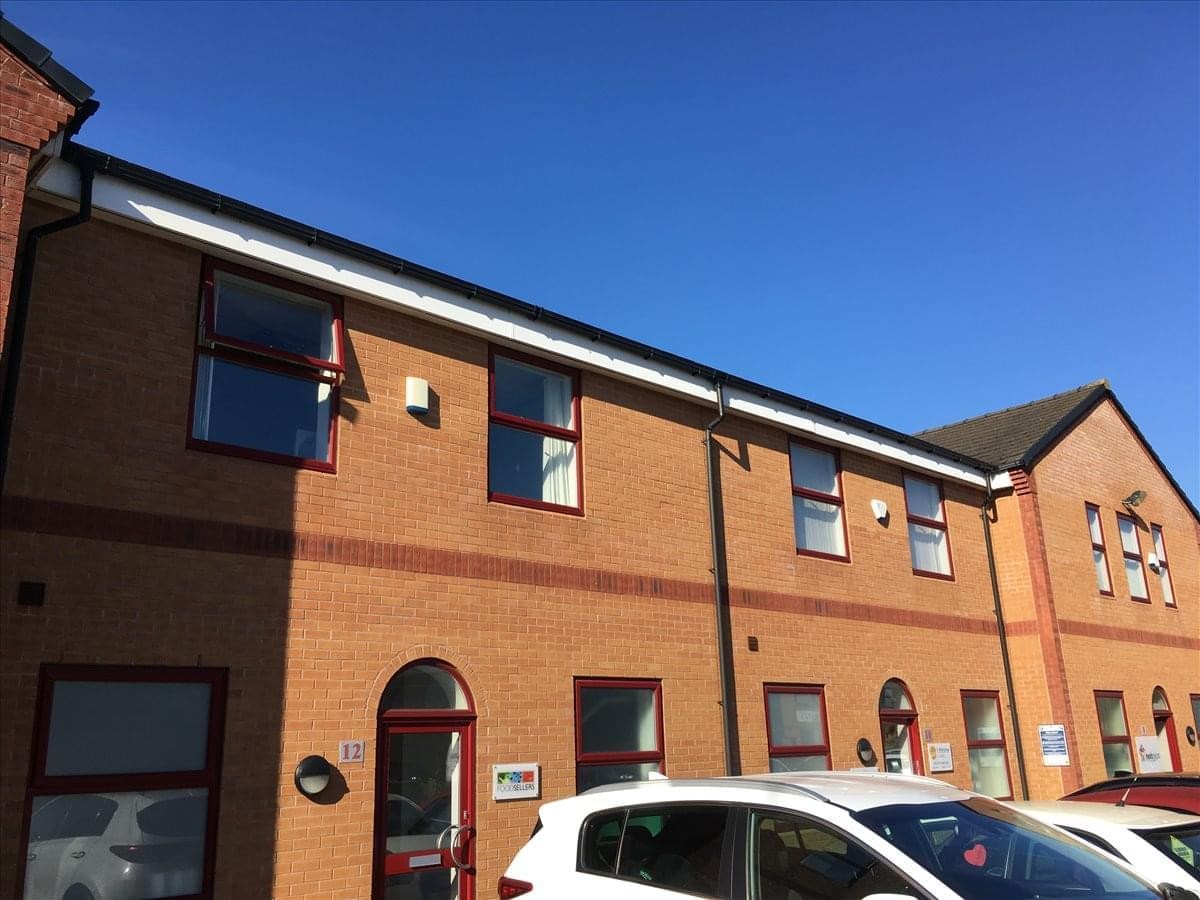 Exterior view of the brick facade at 10B & 12B Tesla Court under a clear blue sky.