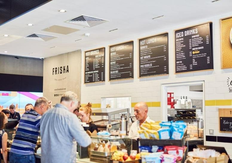 Lively cafe and bistro at Landmark House, Station Road, Cheadle, with menu boards and staff serving customers.