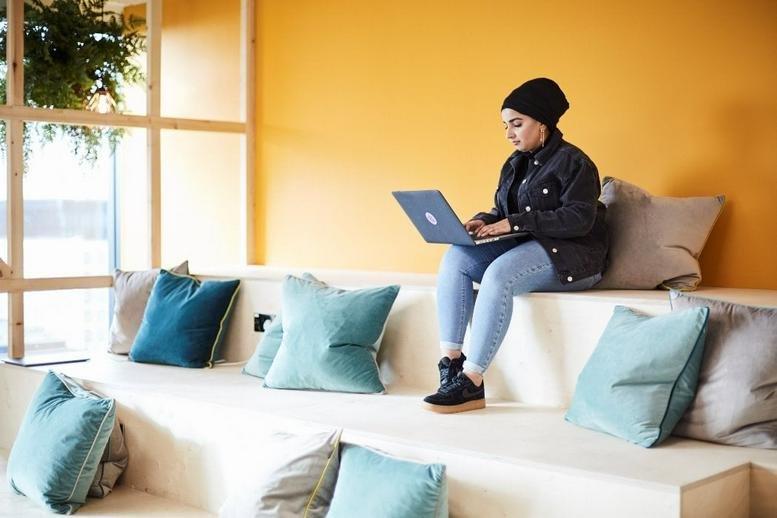 Bright breakout area at NEO, Charlotte Street with tiered wooden seating and colorful cushions.