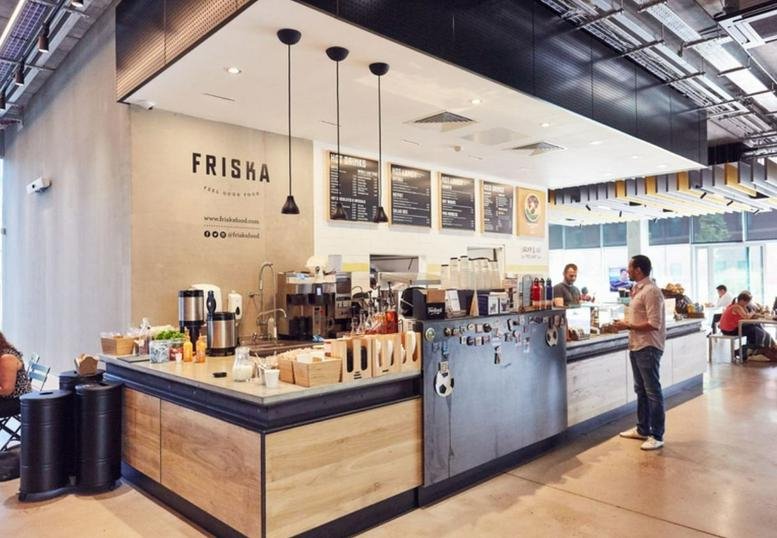 Spacious communal cafe area at Station House, Stamford New Road with wooden counters and modern lighting.
