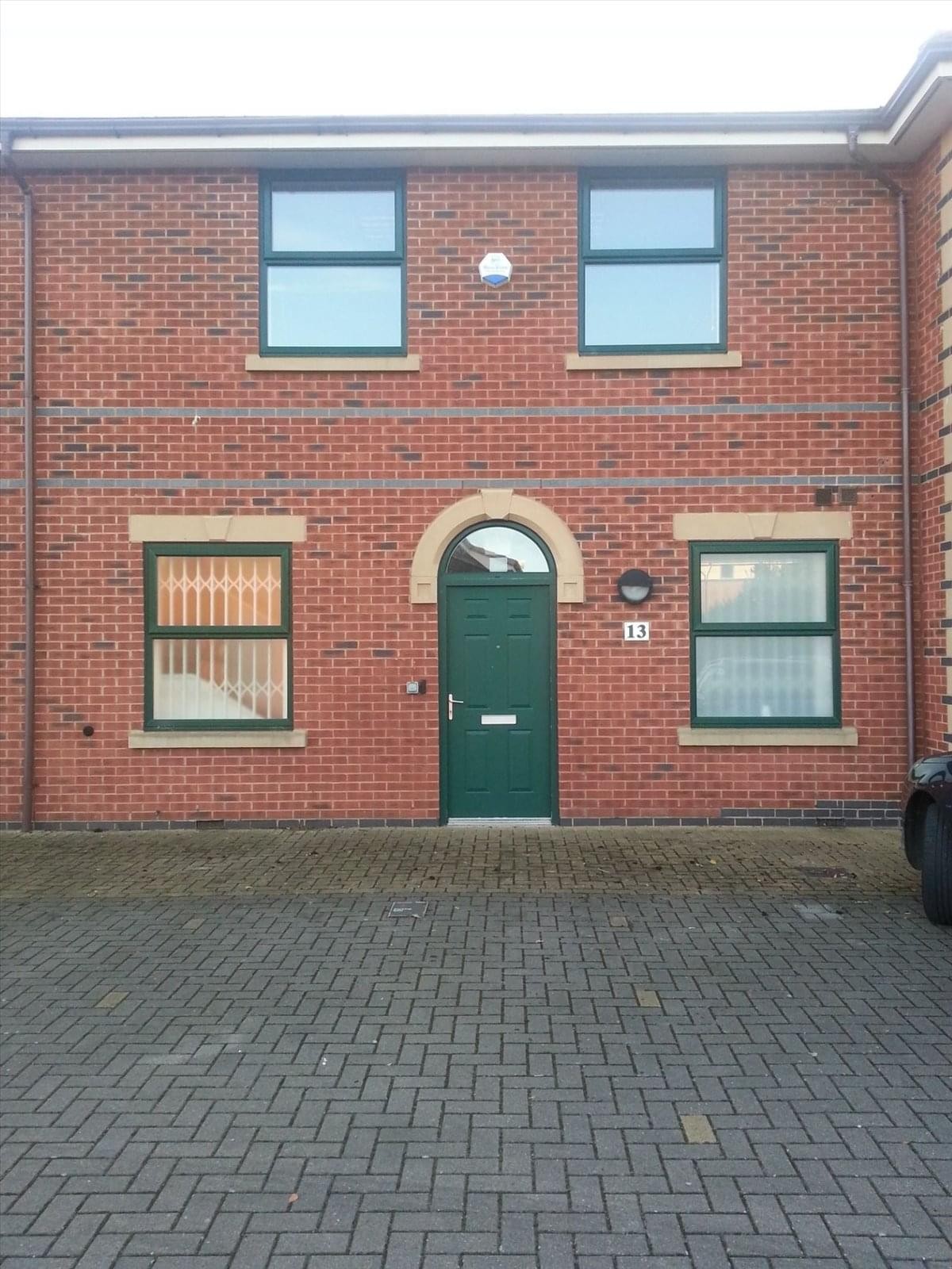 Red brick exterior and green arched entrance of Wheatstone Court, Waterwells Business Park.