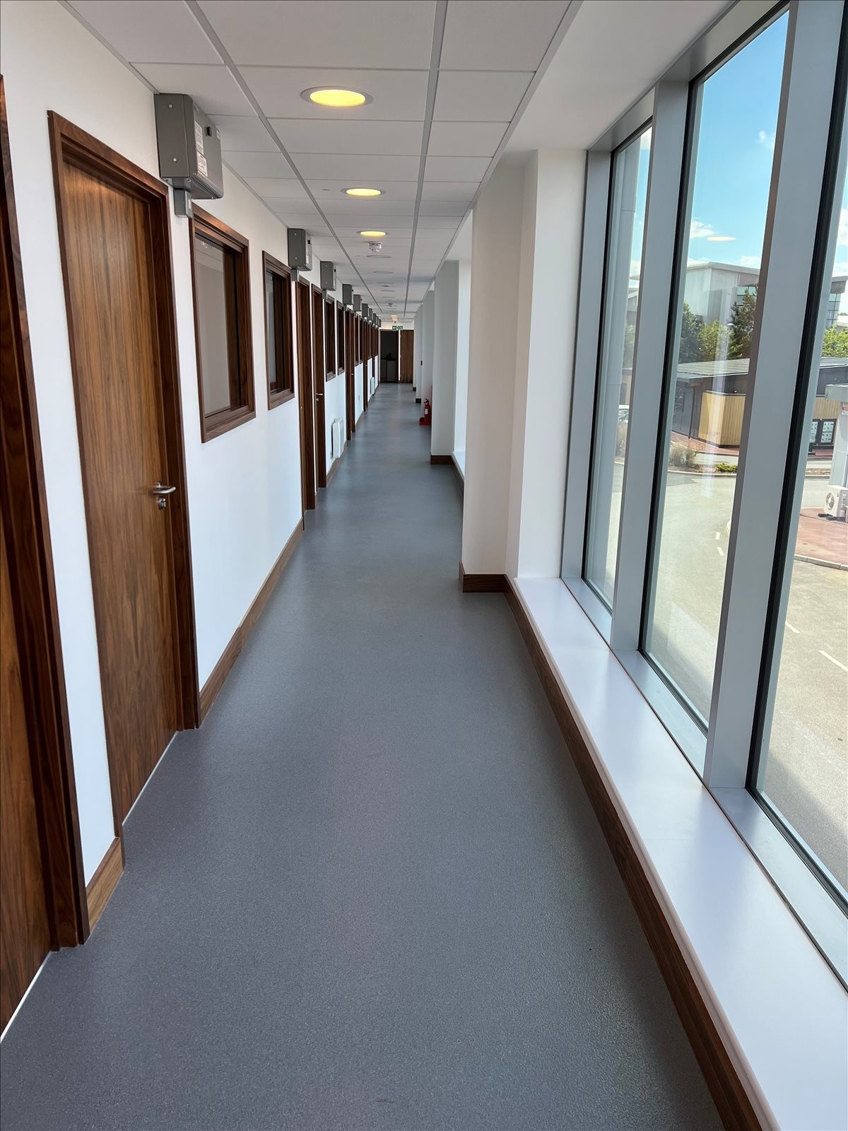 Bright, modern corridor at Whittle Way, Stevenage, Hertfordshire with large windows overlooking the street.