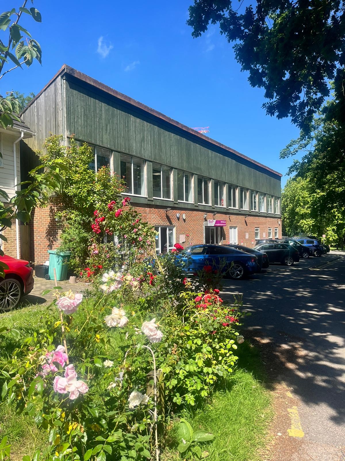Exterior of the brick and timber-clad building at Willow Walk, Locksbottom, Orpington with roses in the foreground.