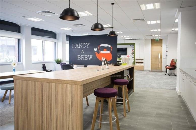 Spacious communal breakout area with a long wooden high-top table and purple bar stools.