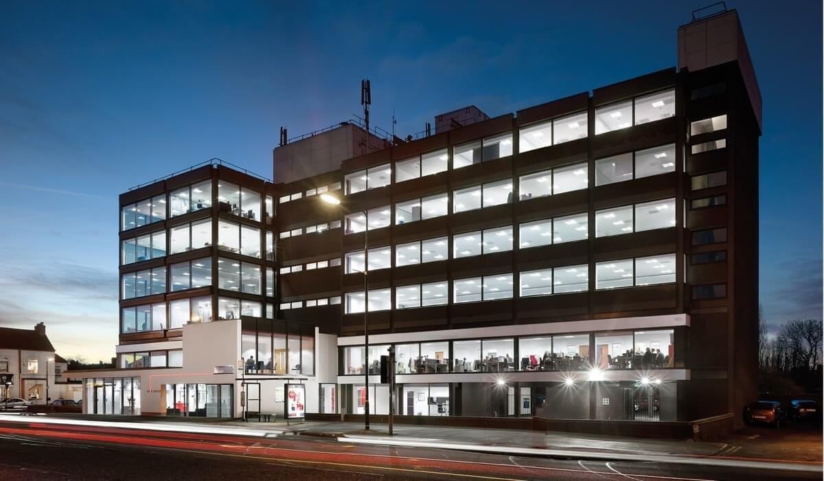 Wide exterior view of the multi-story office building illuminated at dusk.