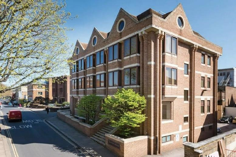 Exterior view of the brick-facade Little Green office building with gabled roof and round windows.