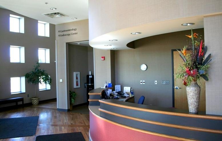Modern reception desk with a large floral arrangement and high windows at Loch Nevis.