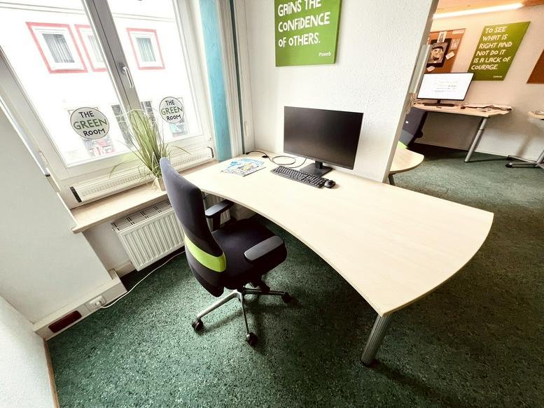 Spacious private office with a curved light-wood desk and a large window at Marktplatz 10.