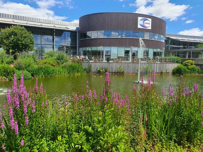 Scenic view of the circular office building across a pond with purple flowers.