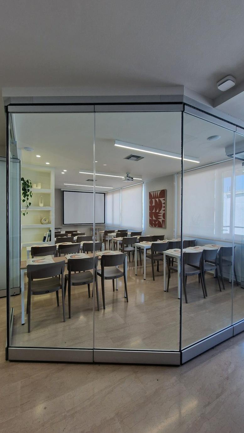 Classroom-style training room at Ntaviou (1st floor) seen through a modern glass partition wall.