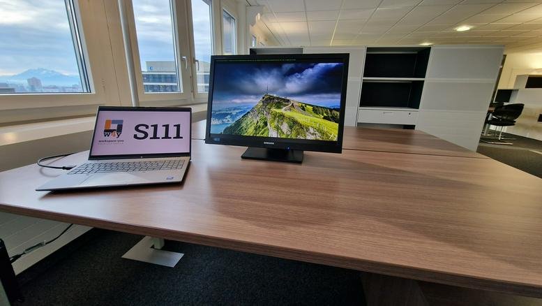 Spacious open-plan office with large windows and modern desks.