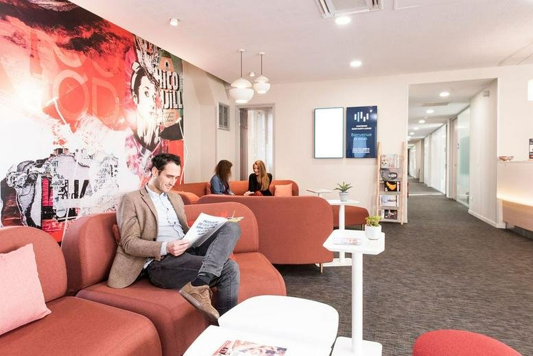 Spacious reception and lounge at 1 Cour du Havre, 75008 Paris, France with vibrant wall art and orange sofas.