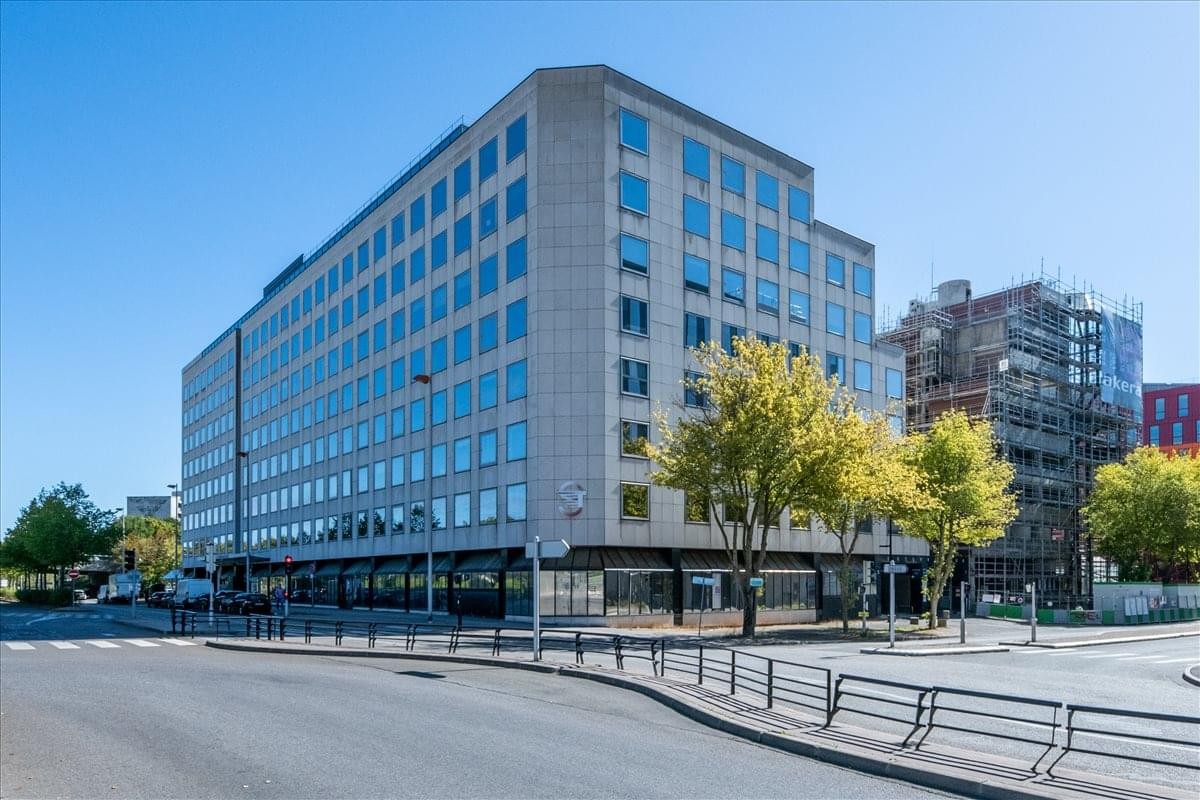 Modern grey exterior building at 1 Rue Georges Stephenson with large windows and surrounding trees.