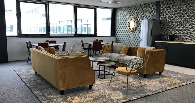 Modern communal area at 10-12 rue des Satellites featuring mustard yellow sofas and cafe seating.